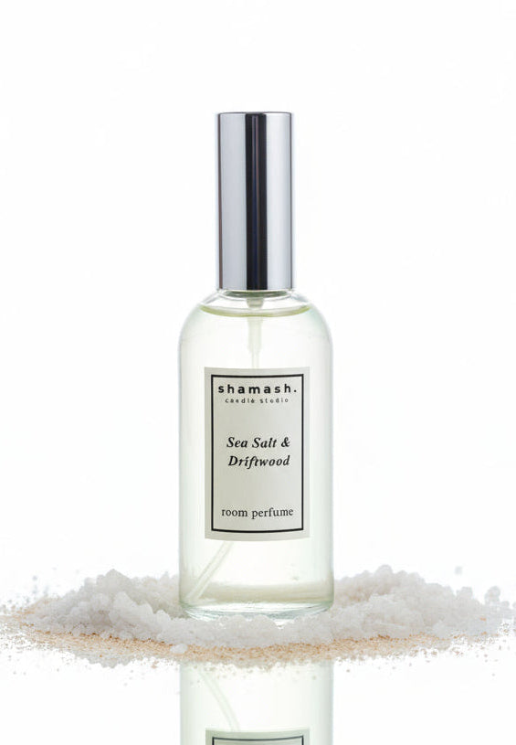 Shamash Sea Salt & Driftwood room perfume bottle on sand with rocks in the background