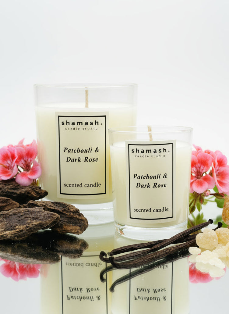 Two shamash candles with vanilla beans and flowers on a table in a living room setting.
