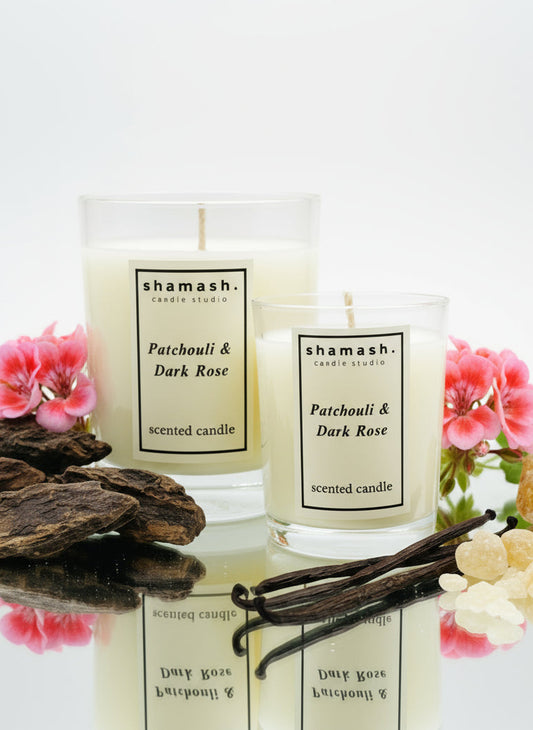 Two shamash candles with vanilla beans and flowers on a table in a living room setting.